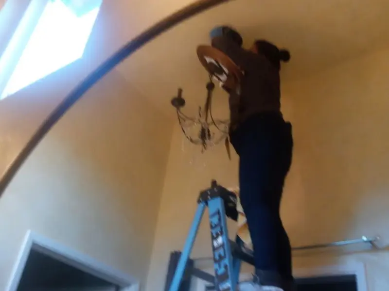 Electrician installing a chandelier in a Layton residence